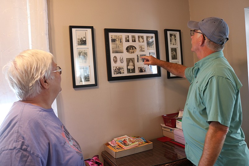 Helen Weiss and Bill Comly look at a collage of old family photos.