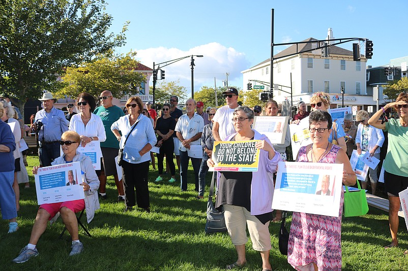 Holding signs, protesters gather in Mark Soifer Park to denounce the state sex education curriculum.