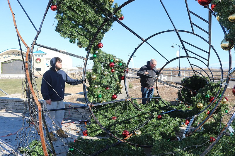 Rileighs Outdoor Decor workers Koby Rollins, left, and Jake Bjorbekk inspect the tree's damaged metal frame.