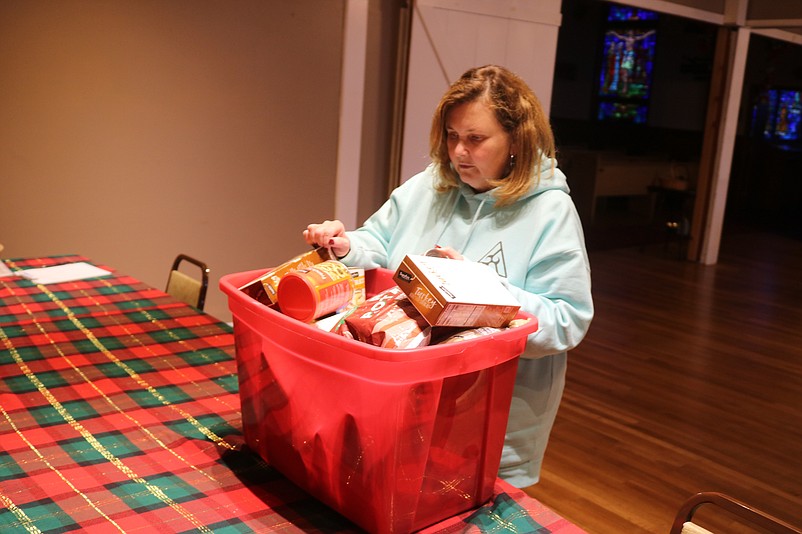 Pastor Melissa Doyle-Waid looks at some of the boxes, bags and cans of food that have been donated by the community for the Christmas dinners.