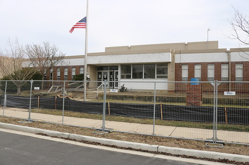 A chain-link fence seals off access to the old school in advance of the building's demolition to make way for construction of a new community center.