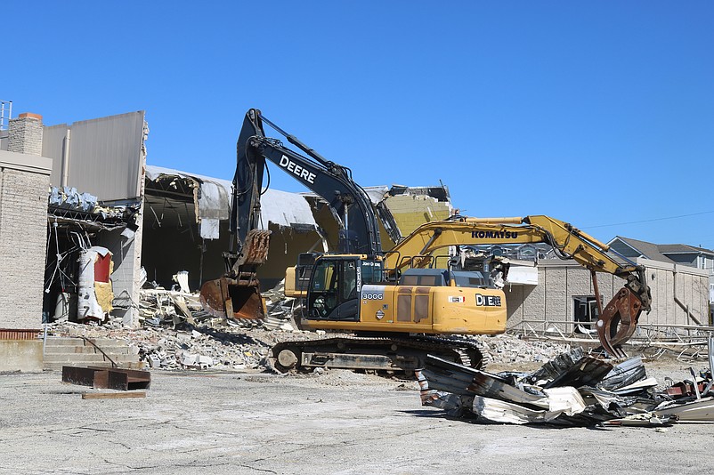 Two excavators work in tandem to demolish the back of the building.