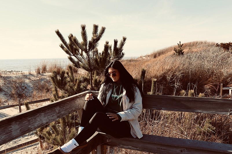 Jake Brown’s girlfriend, Alex Valentini, models WoodLuck apparel while sitting beachside. (Photos courtesy of Jake Brown)