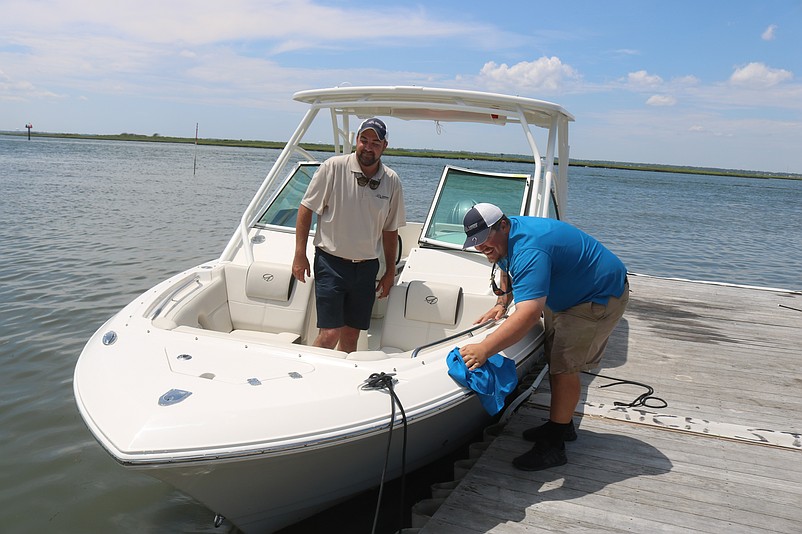 Sean McNulty, Carefree Boat Club's co-owner and membership director, and Kodi Segich, manager of the new Margate location, polish up one of the boats at the dock.