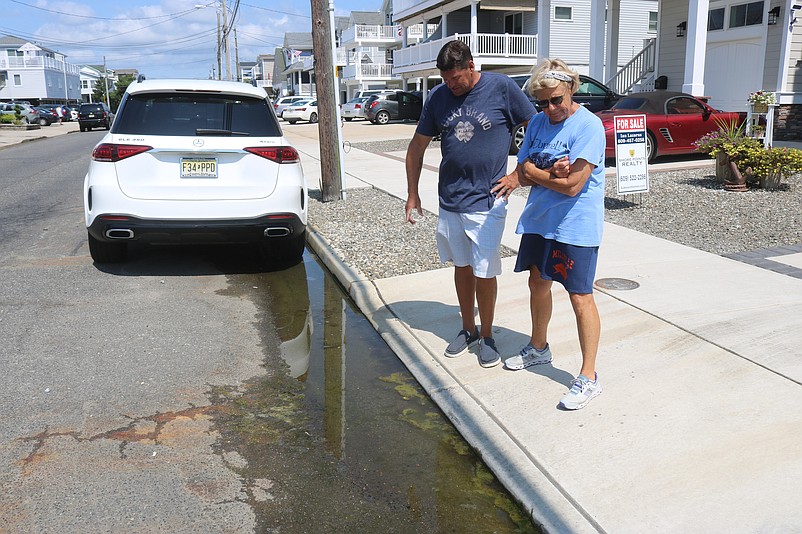 Neighbors Fred Caspar and Mary Corson, residents of 38th Street, look at the stagnant water lurking in the gutter in front of their homes in 2023.