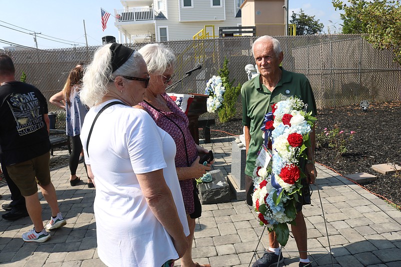 Cullinane's sisters, Jeanne Santucci and Maura Fernandez, and Michael Cullinane Jr.'s grandfather, Eddie Rumer, look at a wreath at the memorial.