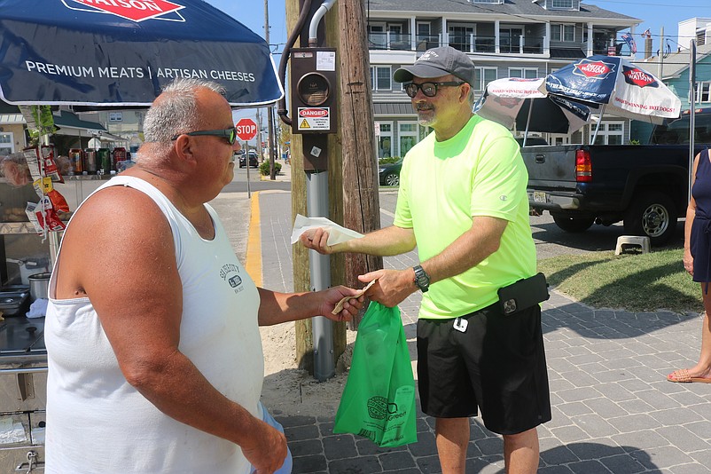 Wayne Stephens, right, buys his last hot dog of the summer season from Mike's Hot Dogs stand owner Mike Beyer.