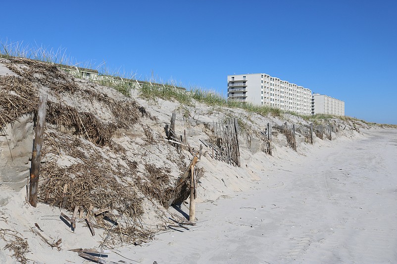 Sand fencing is ripped apart by the storm-tossed ocean.