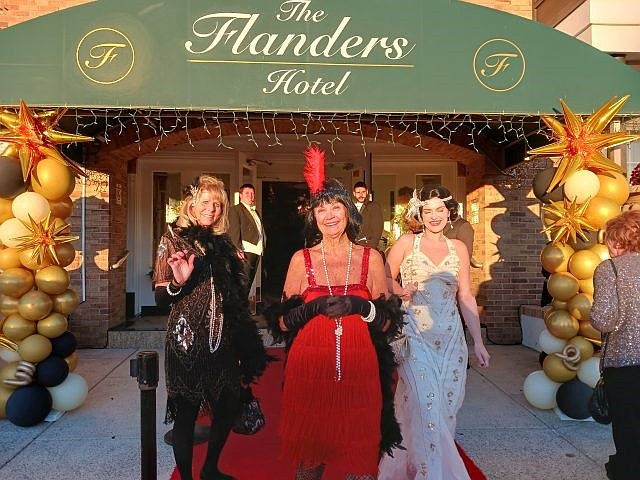 From left, Lynn Wood, Mary Diehl and Hillary Wilson show off their flapper girl outfits while making a grand entrance on the red carpet for the centennial celebration.