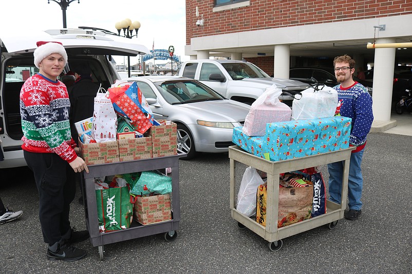 Volunteers Joseph Rutledge, left, and R.J. Seib use carts to load up gifts in a cargo van.