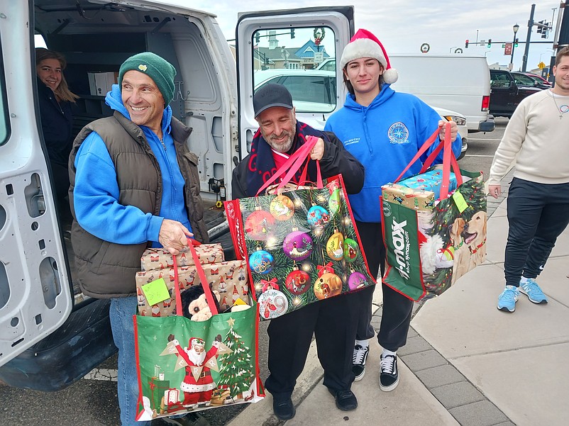 From left, Mark Evangelisti, Mayor Leonard Desiderio and Liza Pellini get ready to load up some gift bags during the food and toy drive in 2023.