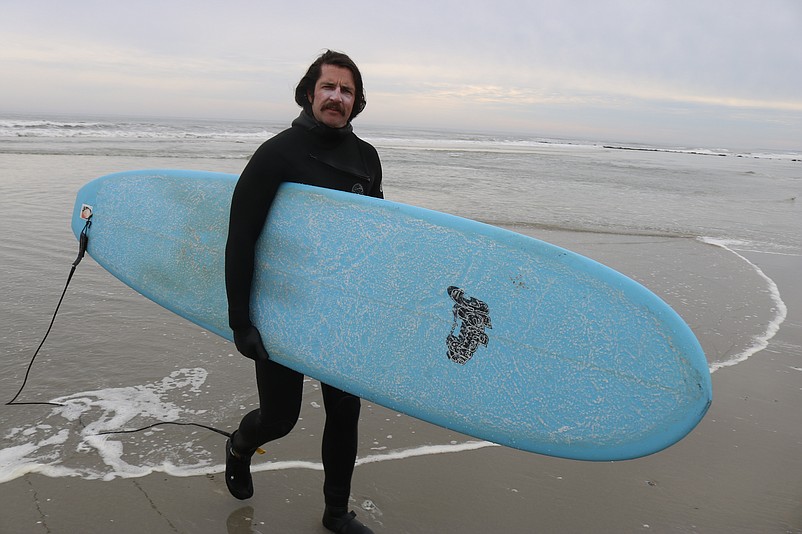 Surfer Kevin Lawrence emerges from the chilly surf after catching some waves.