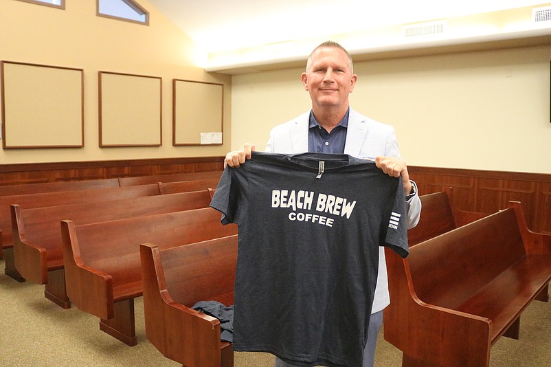 Beach Brew USA owner John Barnes holds up one of the company's T-shirts.