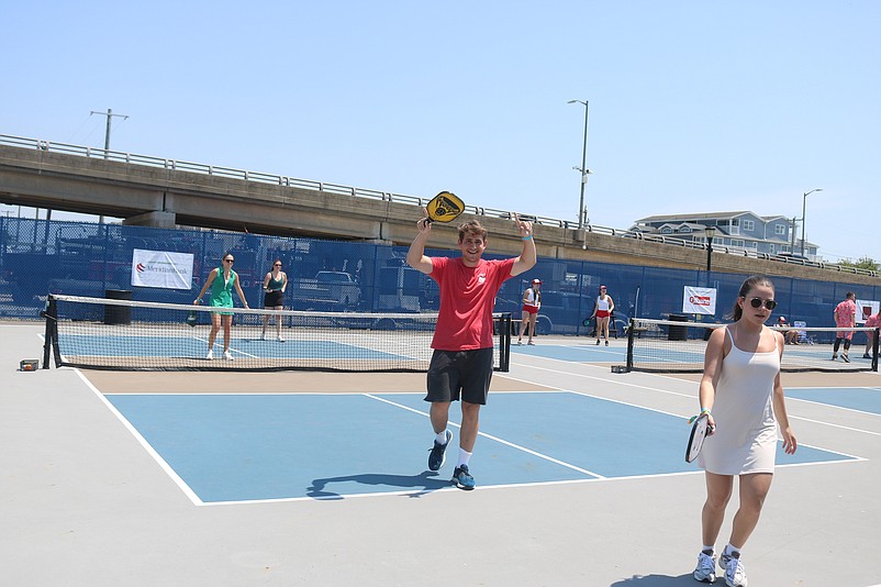 One pickleball player raises his arms in celebration.