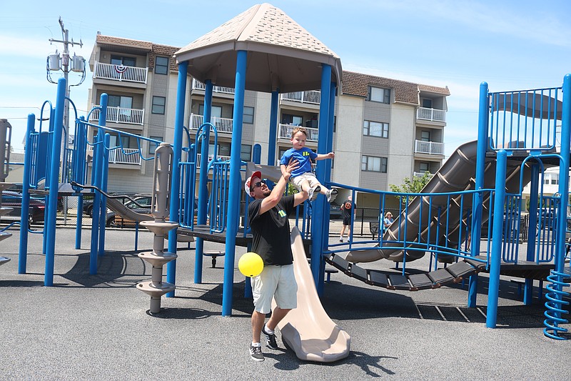 Jake Seymour of Tuckahoe gives his son, Vincent, a lift after some fun on the JFK Boulevard playground sliding board in the summer of 2024.