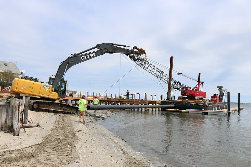 Workers take pilings and install them in the water.