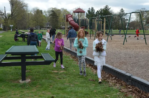 North Wales Elementary School students clean up leaves and debris near the school playground for Earth Day in 2017. (Photo courtesy of North Penn School District)