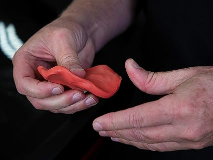 Hands holding Meguiar's Aggressive clay bar for wheels. 