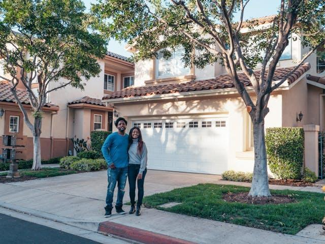 A couple standing in front of a house in one of New Jersey's top suburbs, showcasing suburban living with tree-lined streets and a well-kept neighborhood.