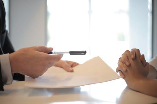 Free Close-up of a contract signing with hands over documents. Professional business interaction. Stock Photo