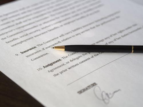 Free Close-up image of a business contract and pen, signed and ready for agreement. Stock Photo