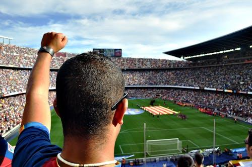 Free A passionate football fan cheers among a crowd at a bustling stadium, creating an electrifying atmosphere. Stock Photo