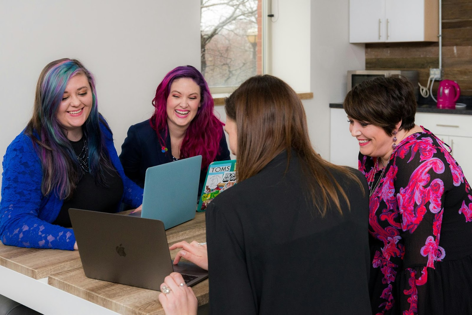 a group of women looking at a laptop