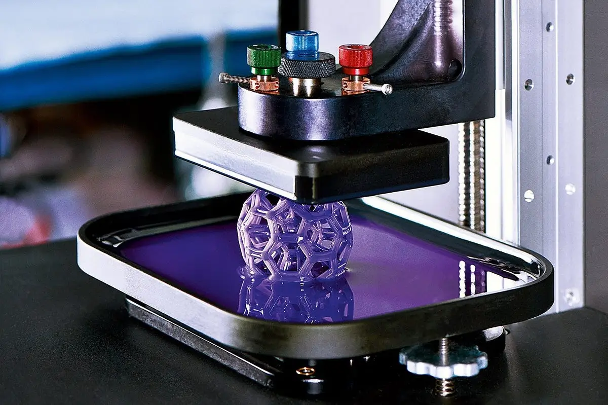 A resin 3D printer crafting a delicate purple lattice design.