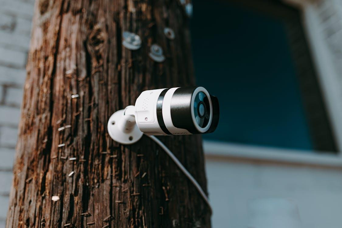 Free Close-up of a modern security camera mounted on a wooden post outdoors. Stock Photo