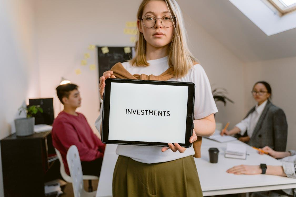 Free Young professional holding tablet in team meeting focused on investments. Stock Photo