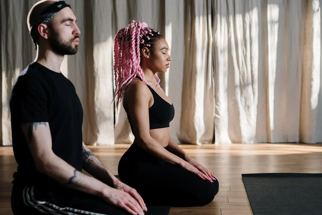 Free Two adults meditate in a serene yoga studio, embracing holistic wellness. Stock Photo