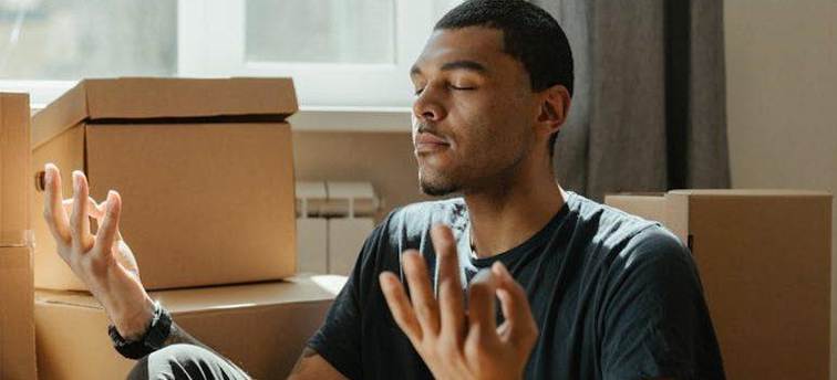 a man meditating surrounded by moving boxes