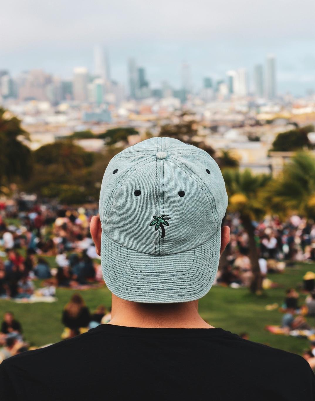 A person wearing a hat looking at a city

Description automatically generated