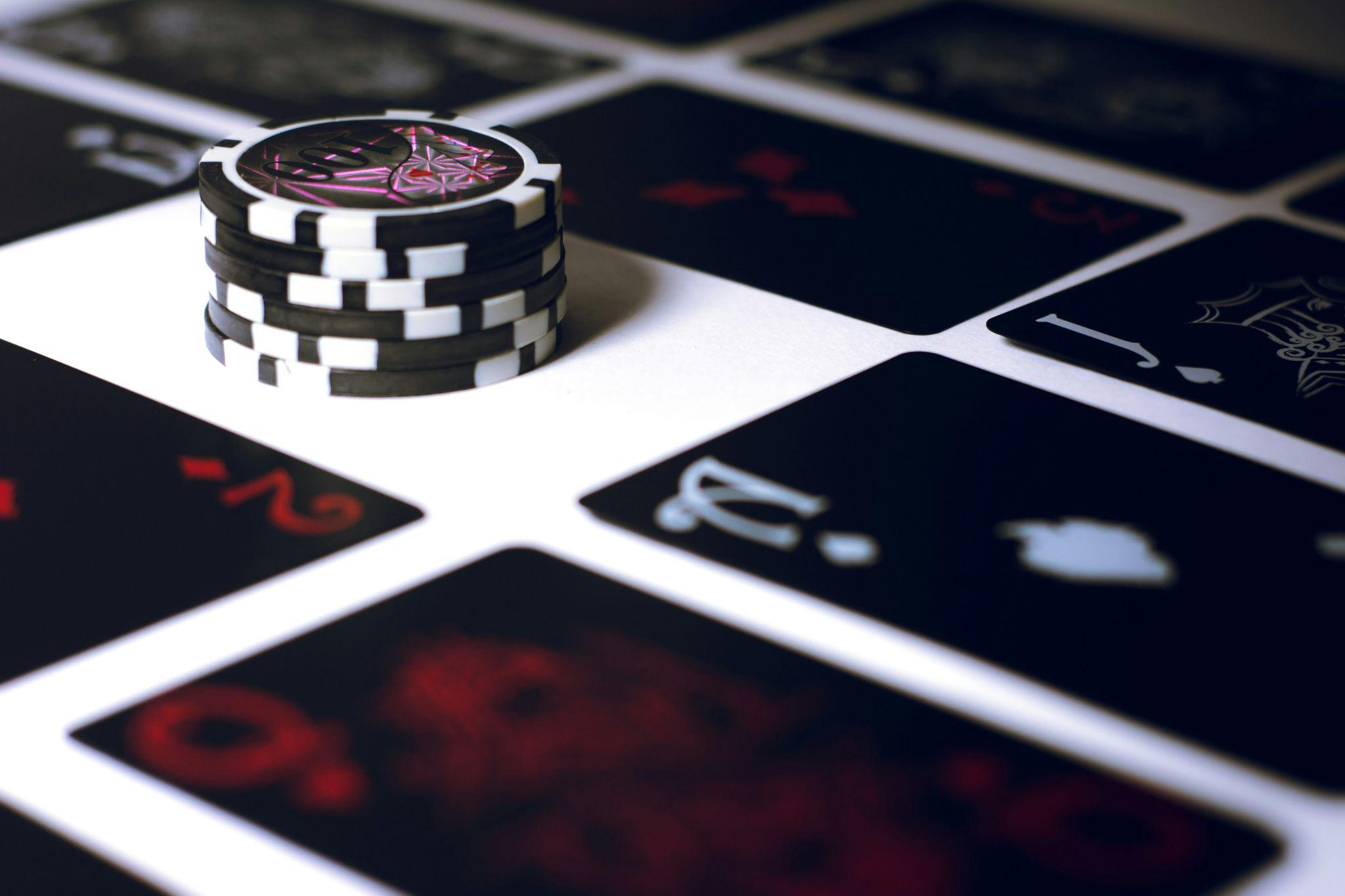 Black poker cards and poker chips on a white table.