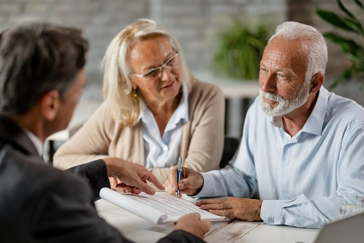 mature couple having a meeting with bank manager and signing lease agreement in the office focus is mature man