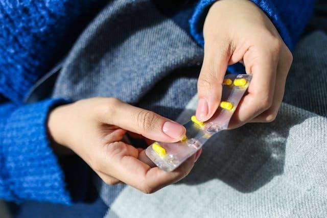 A woman holding yellow pills