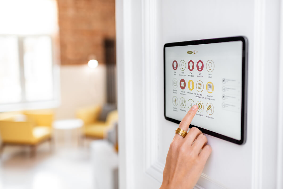 User interacting with a smart home control panel to manage advanced protection technologies like surveillance, access control, and automation.