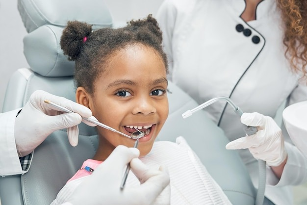happy afro kid on regular check up of teeth in dental clinic