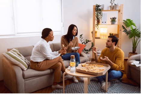 Roommates eating pizza together at shared apartment