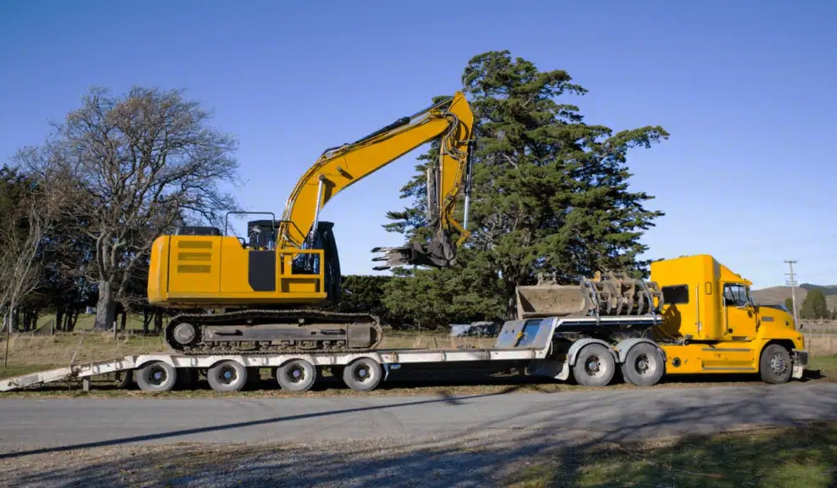 Yellow excavator transported on a heavy-duty flatbed trailer